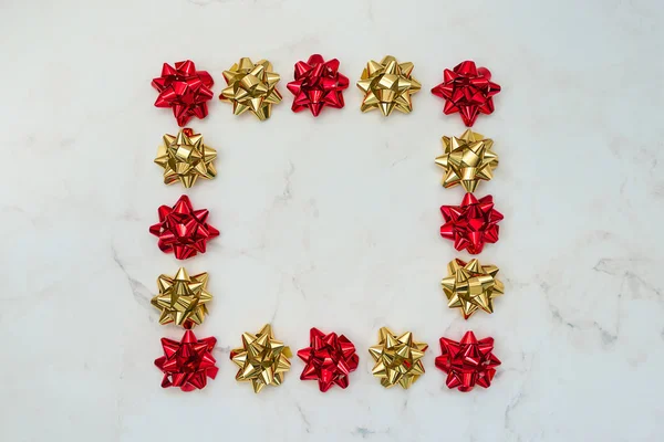 Red and gold festive bows on white marble background. Backdrop for cards, invitations, greetings.