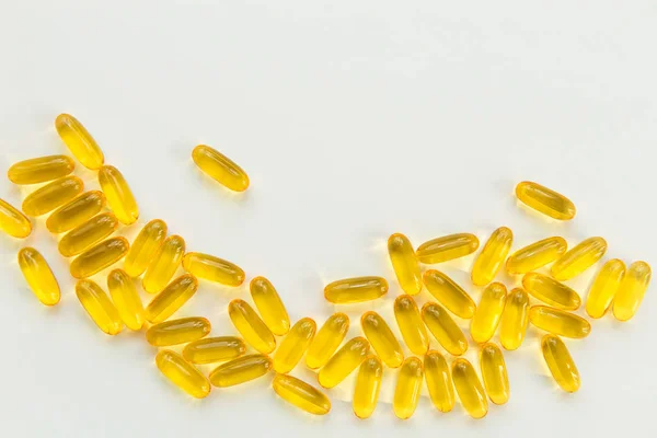 Gold fish oil capsules on white background with copy space. Health and pharmacy theme
