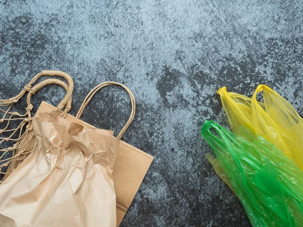 Plastic bags with eco friendly bags for shopping, flat lay on gray background with copyspace. Zero waste concept, plastic free items.