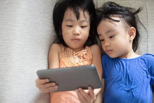 Azjatycki Chiński Małe Siostry Pomocą Tabletu Leżąc Kanapie Salonie — Zdjęcie stockowe