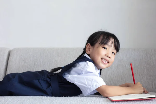 リビング ルームでソファの執筆本を置くアジア中国少女 — ストック写真