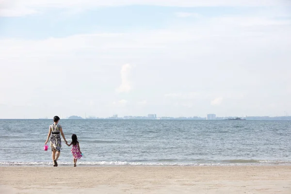 Asian Chinese mum and daughters playing sand together at beach outdoor