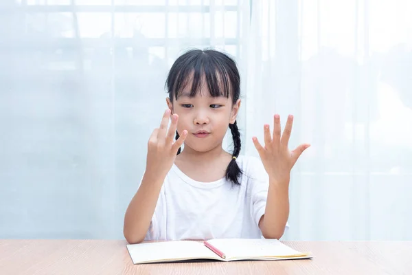 Asyalı küçük Çinli kız evde parmak sayarak matematik yapıyor