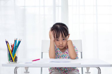 Asian Little Chinese girl doing homework at home clipart