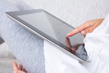 Çocuk evde oturma odasında oynarken dijital tablet eller