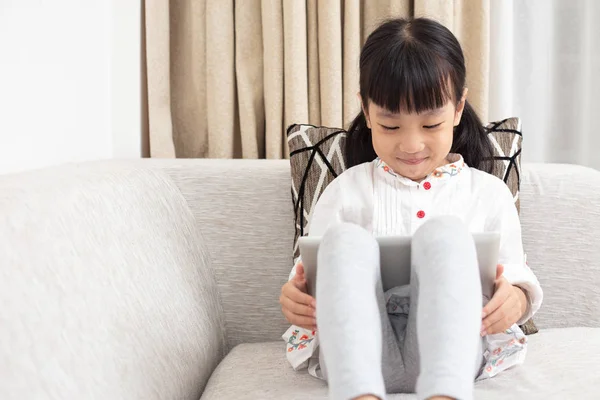 Azjatycki Chiński Dziewczynka Siedzi Kanapie Odtwarzanie Cyfrowych Tablet Salonie Domu — Zdjęcie stockowe