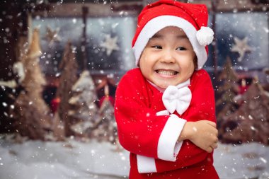 Asian Chinese little girl playing with snowflakes outdoor during christmas eve clipart