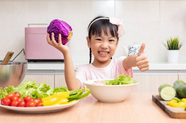 Asyalı Çinli küçük kız mutfakta ev salatası yapmak