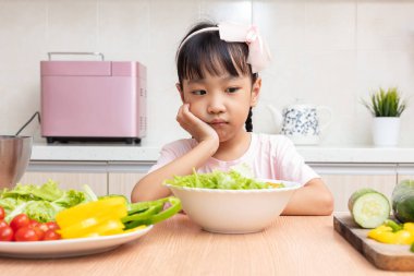 Asyalı Çinli küçük kız salata evde mutfakta yemek