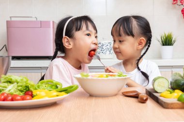 Asyalı Çinli küçük kız salata evde mutfakta yemek