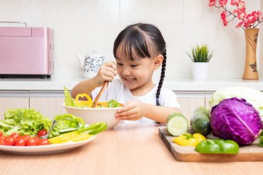 Asyalı Çinli küçük kız mutfakta ev salatası yapmak