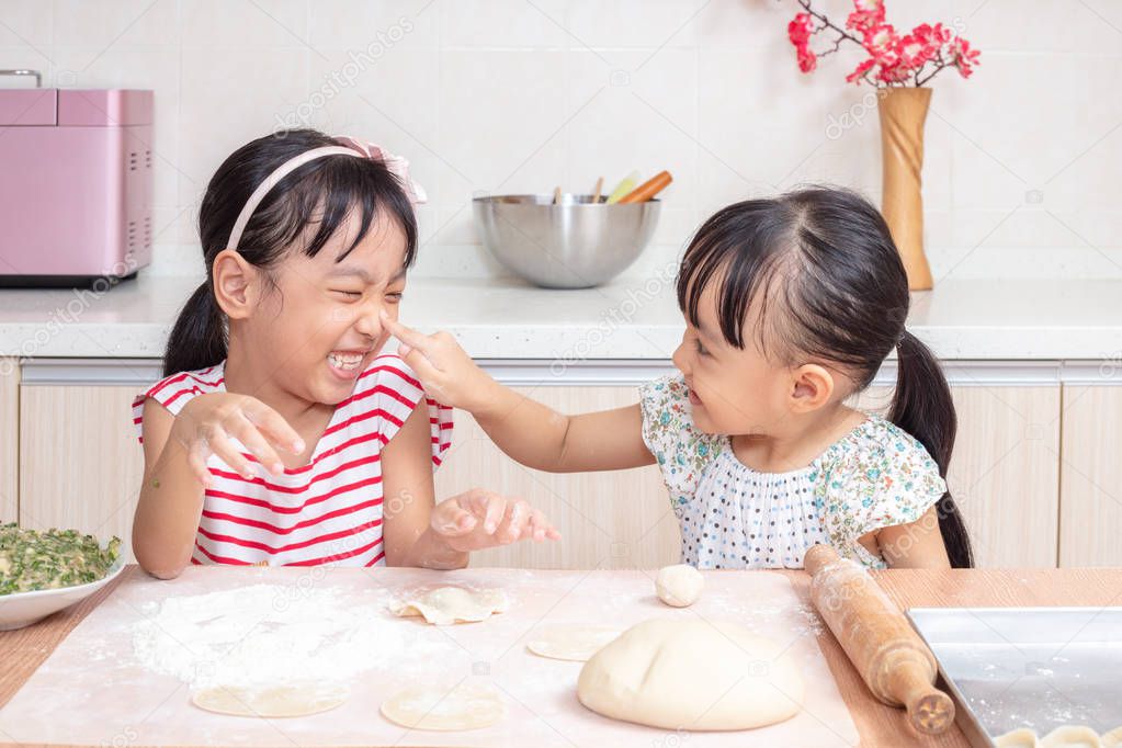 Asian Chinese little sisters making dumpling in the kitchen at home