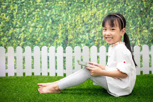 Azjatycki Dziewczynka Chiński Siedząc Trawie Grając Tabletu Zewnątrz Park — Zdjęcie stockowe