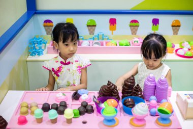 Asyalı Çinli küçük kız kardeş Ice cream rol yapma kapalı Bahçesi depolamak