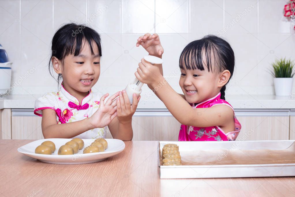 Asian Chinese little sisters making moon cake in the kitchen at home