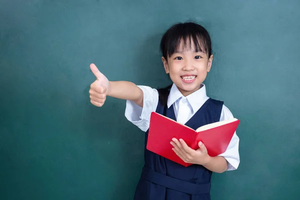 亚洲中国的小女孩在制服显示竖起大拇指反对绿色黑板在课堂上 — 图库照片