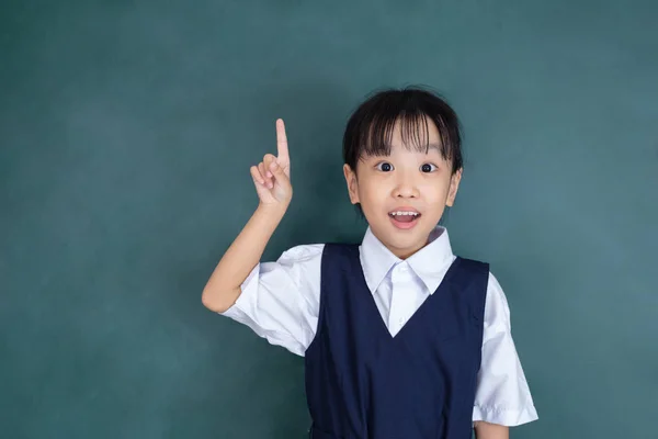 亚洲中国的小女孩在制服指着手指对绿色黑板 — 图库照片