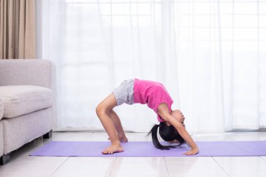 Asyalı Çinli küçük kız pratik yoga poz evde oturma odasında bir mat