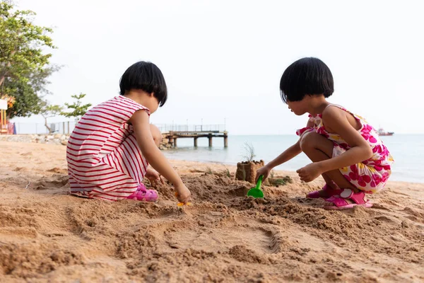 Aziatische Chinese zusjes spelen zand op het strand — Stockfoto