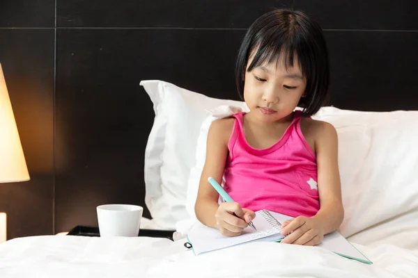 Ασιατικό μικρό κινέζικο κορίτσι κάνει την εργασία στο κρεβάτι — Φωτογραφία Αρχείου