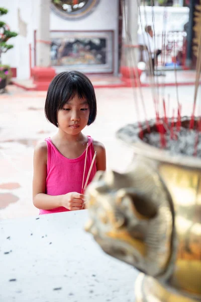 Asiático pouco chinês menina orando com queima de incenso varas — Fotografia de Stock