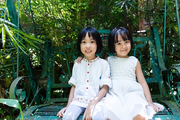 Asya Küçük Çinli Sisters bankta oturan — Stok fotoğraf
