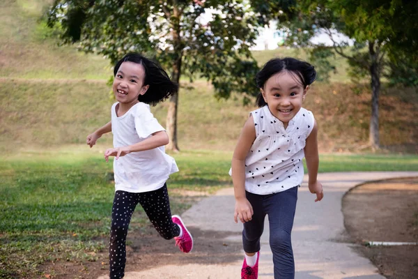 Asiatiska lilla kinesiska systrar kör glatt Royaltyfria Stockfoton