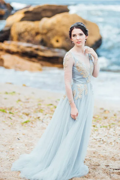 Mariée dans une robe de lumière bleue marchant le long de l'océan — Photo