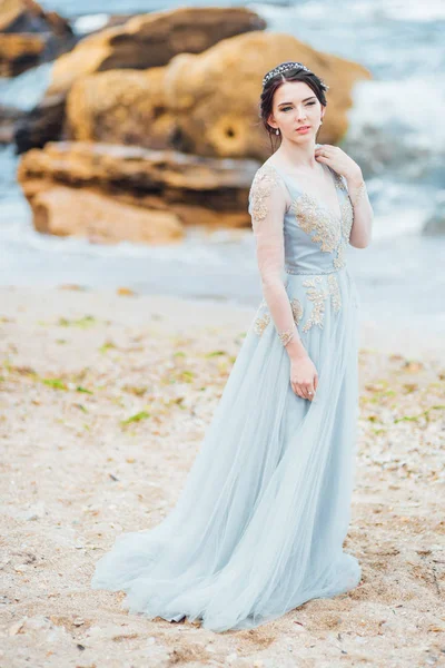 Novia en un vestido de luz azul caminando a lo largo del océano — Foto de Stock
