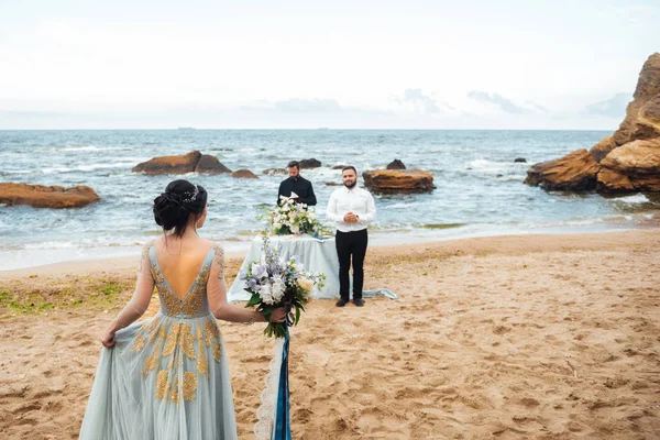 Pareja de boda en el océano con un sacerdote —  Fotos de Stock