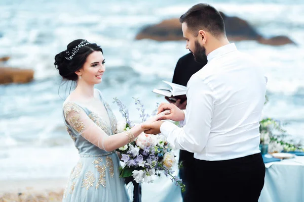 Casal de casamento no oceano com um padre — Fotografia de Stock