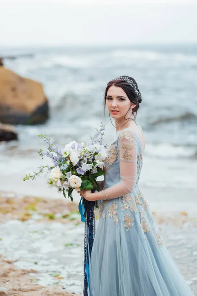 Mariée avec un bouquet de fleurs sur la plage — Photo