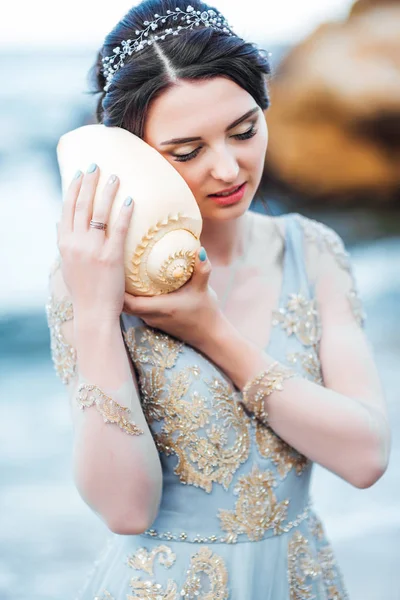 bride with a big shell on the beach