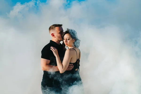 黒い服を着た男と女が白い煙の中で抱きつく — ストック写真