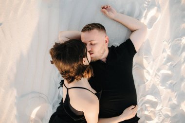 Genç çift, bir adam ve siyah elbiseli neşeli bir kız kar beyazı çölünde yürüyorlar.