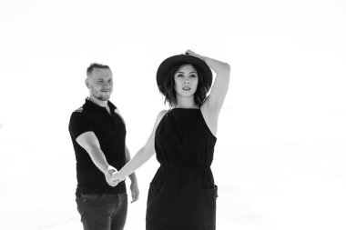 Genç çift, bir adam ve siyah elbiseli neşeli bir kız kar beyazı çölünde yürüyorlar.