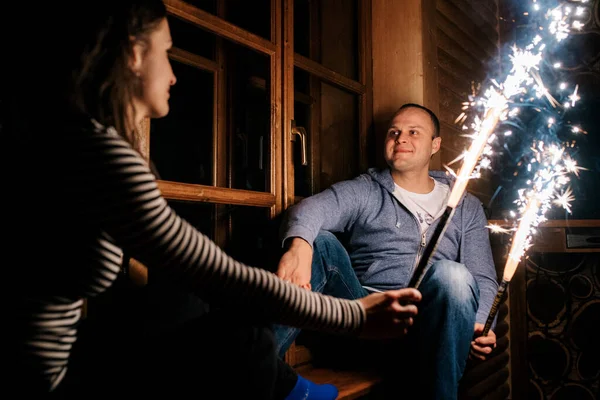 一个男人和一个女孩深夜在一间木屋里点燃了火花 — 图库照片