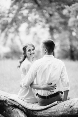 Beyaz gömlekli mutlu bir adam ve turkuaz elbiseli bir kız, gelin ve damat orman parkında yürüyorlar.