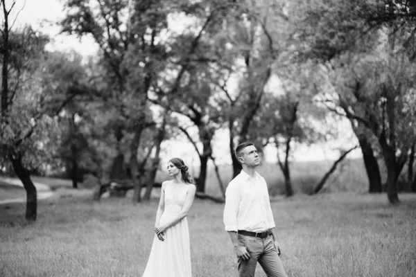白いシャツを着た幸せな男とターコイズブルーのドレスを着た女の子花嫁と新郎が森林公園を歩いています — ストック写真
