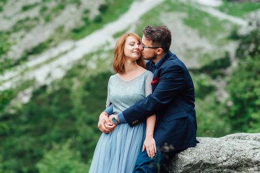 Genç bir çift göl kenarında yürüyüş yapıyor. Etrafı Karpat dağlarıyla çevrili.