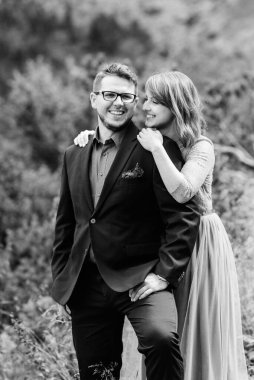 Genç bir çift göl kenarında yürüyüş yapıyor. Etrafı Karpat dağlarıyla çevrili.