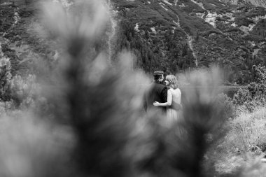 Genç bir çift göl kenarında yürüyüş yapıyor. Etrafı Karpat dağlarıyla çevrili.