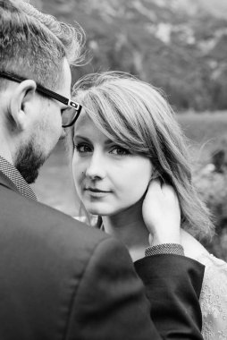 Genç bir çift göl kenarında yürüyüş yapıyor. Etrafı Karpat dağlarıyla çevrili.