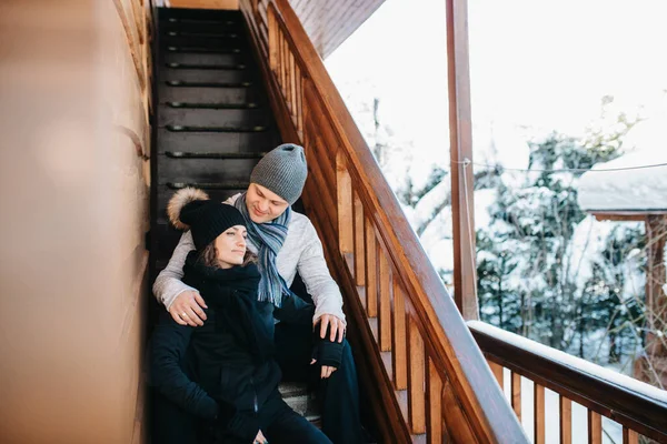 在冬季的群山中 一对年轻夫妇在一座被雪覆盖的木头房子的门廊上 一男一女 — 图库照片