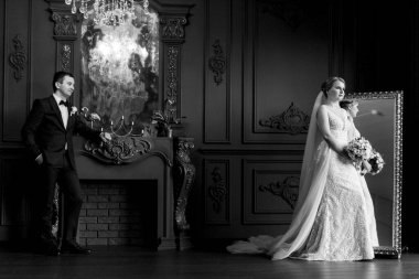 Genç bir çift karanlık bir stüdyoda, bir ayna ve bir avizeyle.