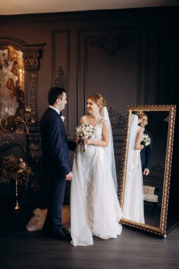 Genç bir çift karanlık bir stüdyoda, bir ayna ve bir avizeyle.