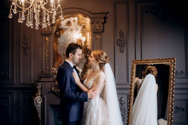 Genç bir çift karanlık bir stüdyoda, bir ayna ve bir avizeyle.