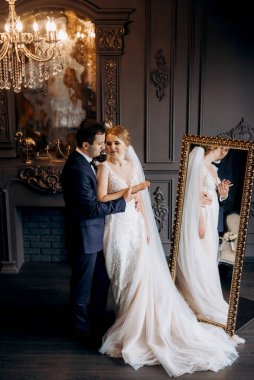 Genç bir çift karanlık bir stüdyoda, bir ayna ve bir avizeyle.