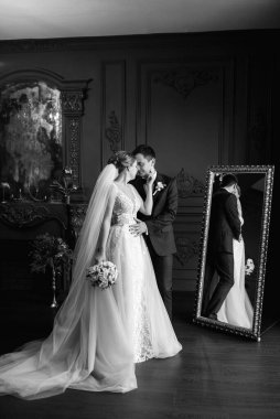 Genç bir çift karanlık bir stüdyoda, bir ayna ve bir avizeyle.