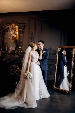 Genç bir çift karanlık bir stüdyoda, bir ayna ve bir avizeyle.